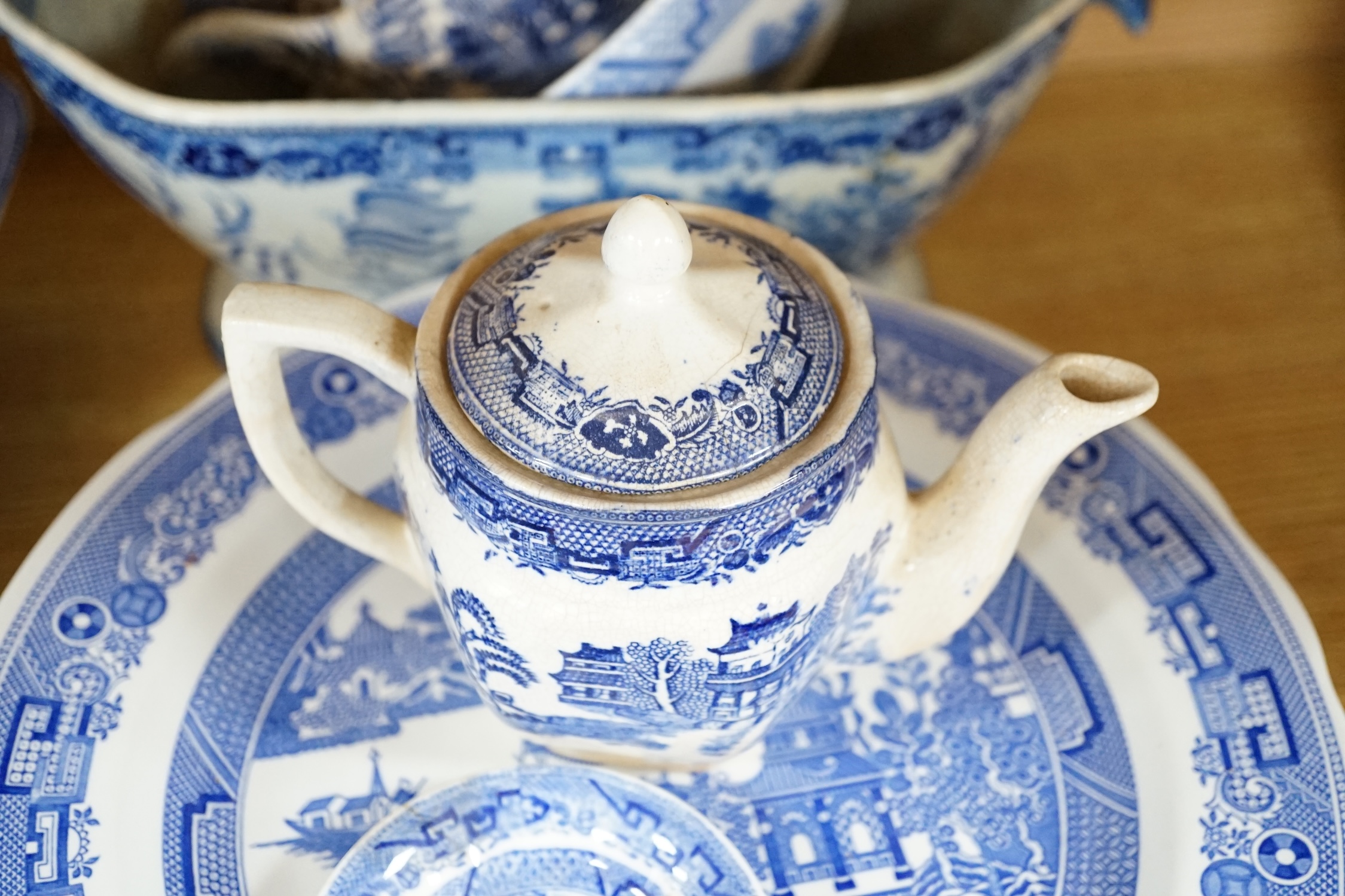 A mixed collection of Willow pattern blue and white dinnerware, including four tureens and covers, plates meat dishes etc. (large quantity). Condition - varied poor to fair to good